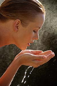 Девушка пьет воду из ладоней